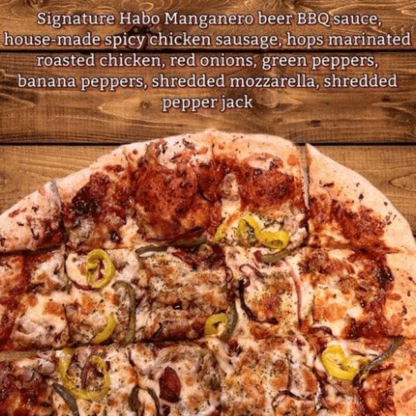 Close-up of a sliced pizza with chicken, red onions, green and banana peppers, and cheese.