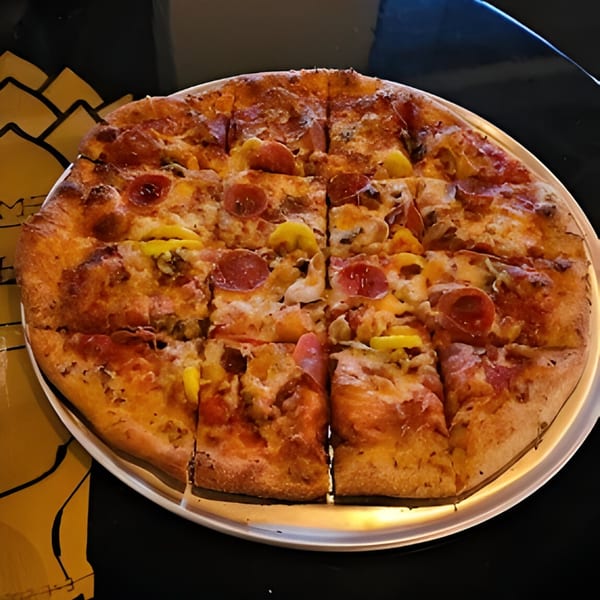A whole pepperoni and banana pepper pizza, cut into squares, on a metal tray.