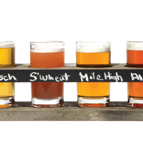 Four Atlantucky Brewing beer flights in a wooden holder with names written in chalk.